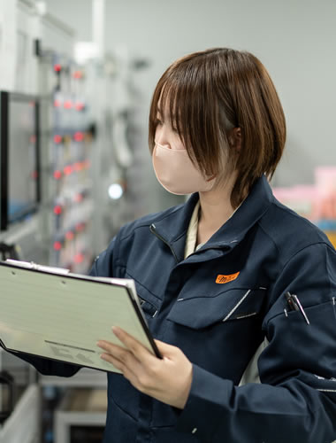工場で設備を確認する作業服姿の社員