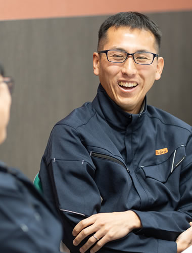 笑顔で語る作業着姿の社員Kさん