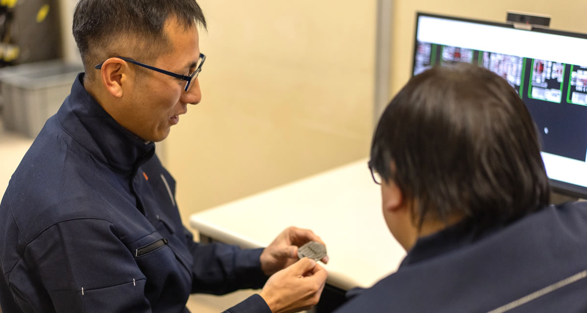 部品を手に打ち合わせる社員たち
