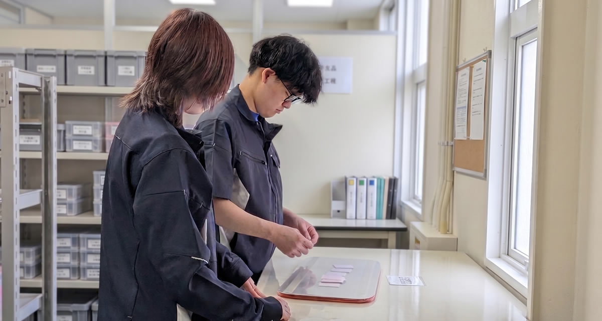 作業台で部品を確認する社員たち