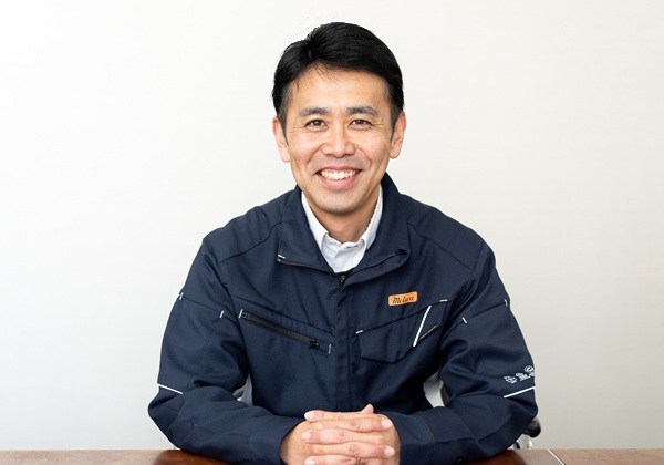 作業着姿でテーブルに座り笑顔を見せる社員