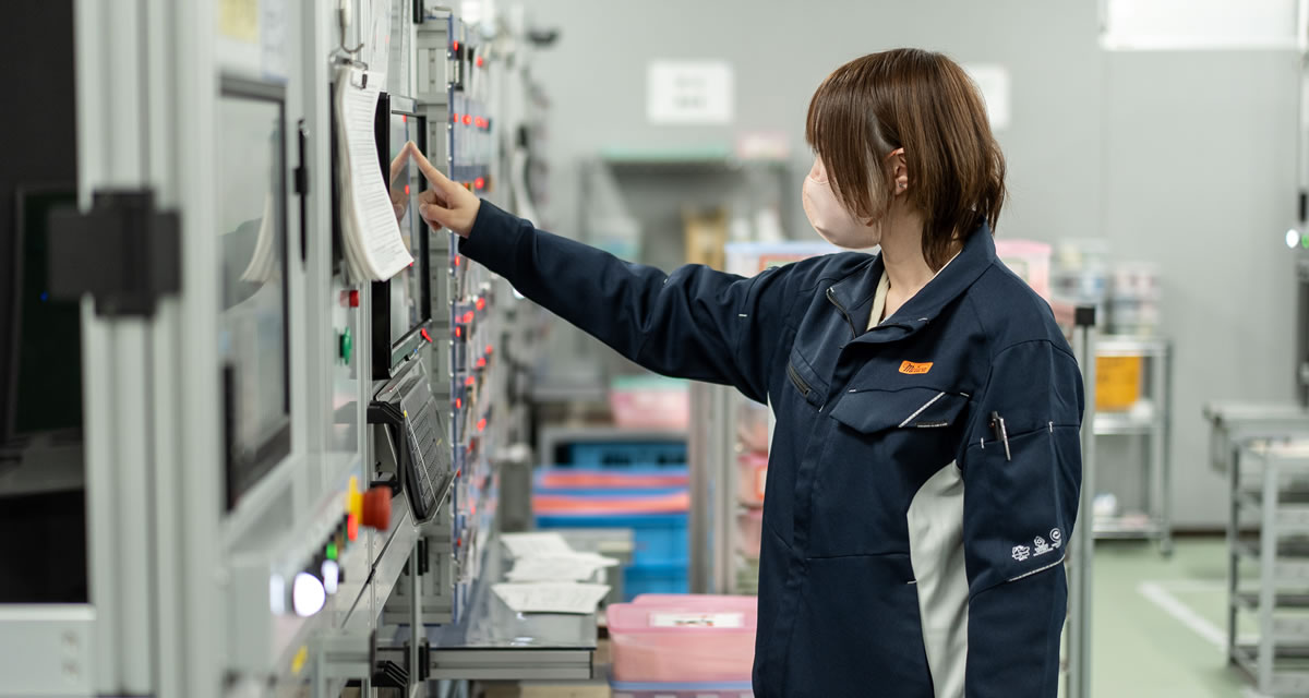 工場で設備を操作する女性社員