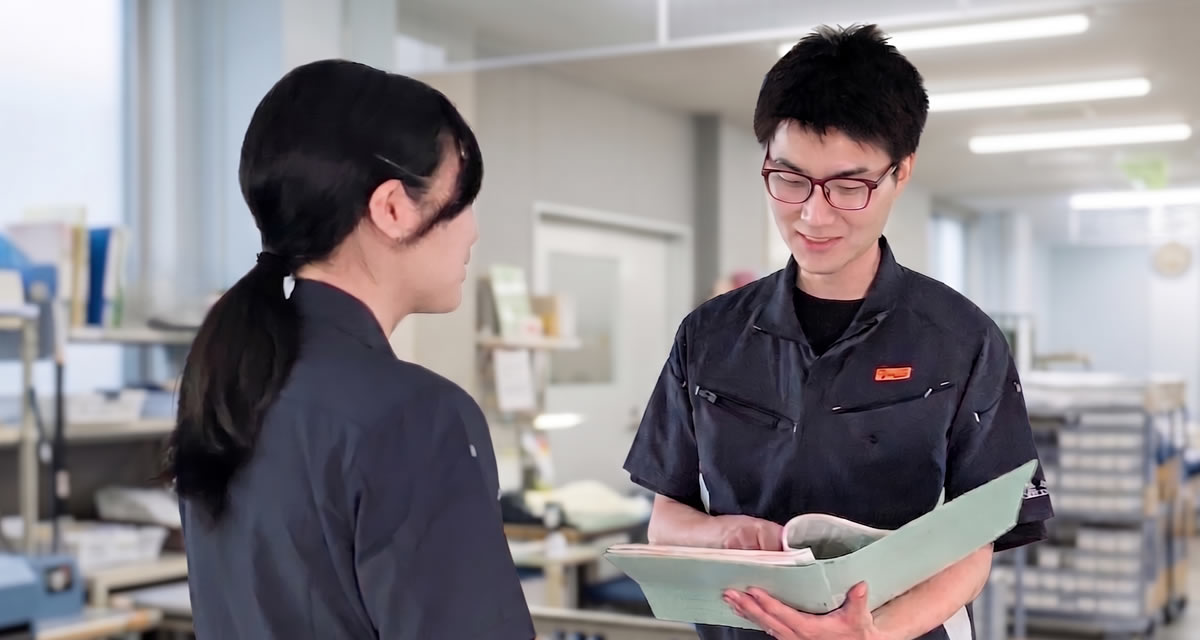 工場内で資料を確認しながら話す社員